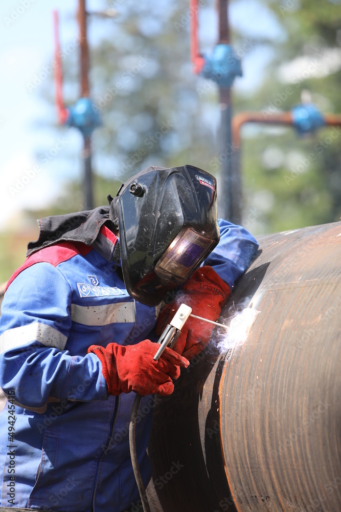 Male welder works. Welding joint of large diameter pipe. High pressure pipe welding for a gas station.