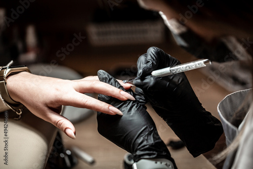 The master uses an electric machine to remove the nail polish during manicure in the salon. Hardware manicure. Quarantine period. Small business and covid-19, coronavirus