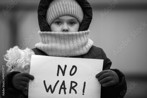 A little refugee girl with tears in her eyes and a placard that says no war. Social problem of refugees and internally displaced persons. Russia's war against the Ukrainian people photo