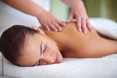 Letting her worries drift away. Shot of a young woman enjoying a back massage at a spa. © Thurstan Hinrichsen/peopleimages.com