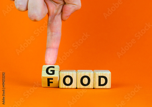 Good food symbol. Doctor turns a wooden cube and changes the word Food to Good. Beautiful orange table orange background. Lifestyle, healthy eating and good food concept, copy space.