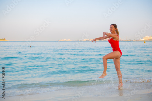 girl jumping on the beach in a red bikin