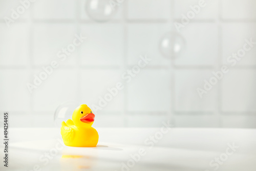 Cute rubber duck on white bathroom countertop with space for text photo