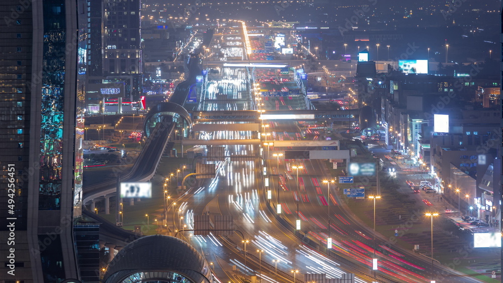 Busy Sheikh Zayed Road aerial night timelapse, metro railway and modern skyscrapers around in luxury Dubai city.