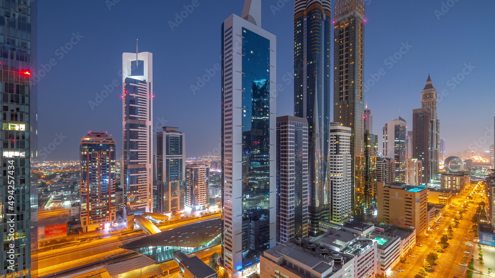 Aerial view of Dubai International Financial District with many skyscrapers night to day timelapse.