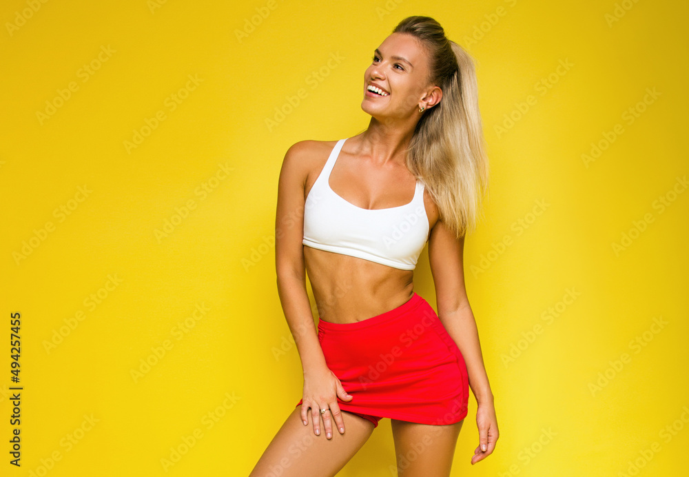 young blonde sports girl in white top and red tennis skirt is