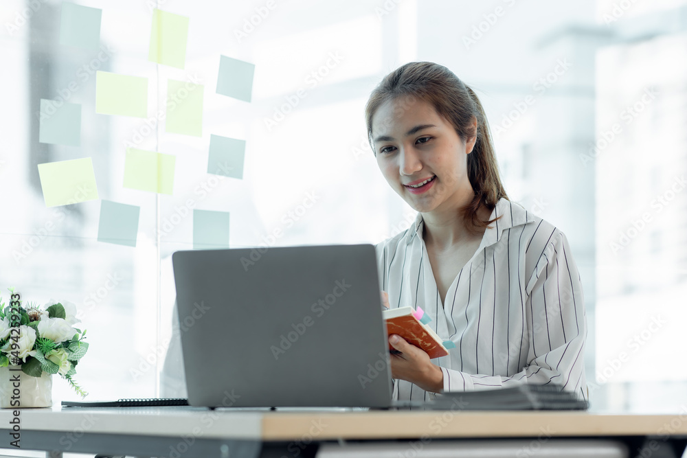 Cropped image of professional Asian businesswoman working at her office via laptop, young female manager using portable computer device while sitting at modern loft, flare light, work process concept Cropped image of professional Asian businesswoman working at her office via laptop, young female manager using portable computer device while sitting at modern loft, flare light, work process concept