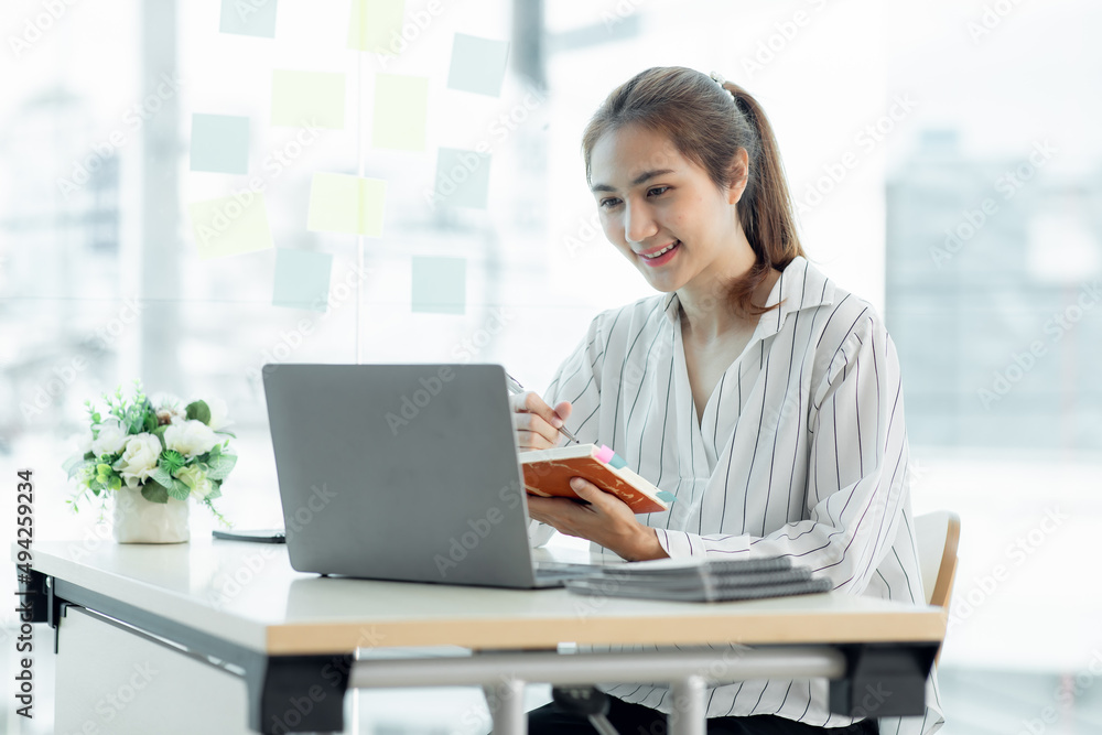 Cropped image of professional Asian businesswoman working at her office via laptop, young female manager using portable computer device while sitting at modern loft, flare light, work process concept