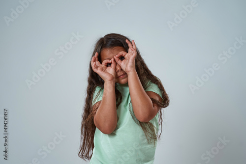 Latin girl look at camera through binoculars sign