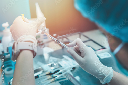 Selective focus on hand of doctor draws a medicinal fluid into the needle syringe for patient vaccination in hospital.