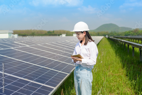 Female engineer wearing helmet in Photovoltaic Cell Farm or Solar Panels Field, eco friendly and clean energy. © tonefotografia