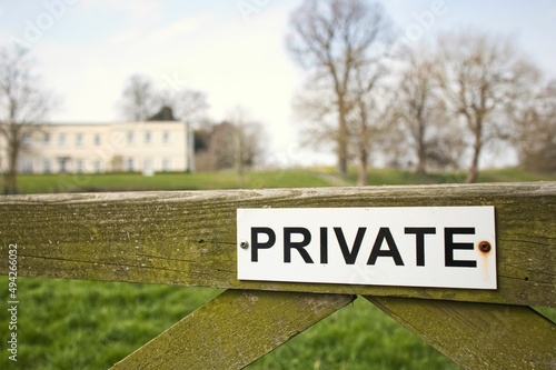 Old wooden gate with private sign and house in the background