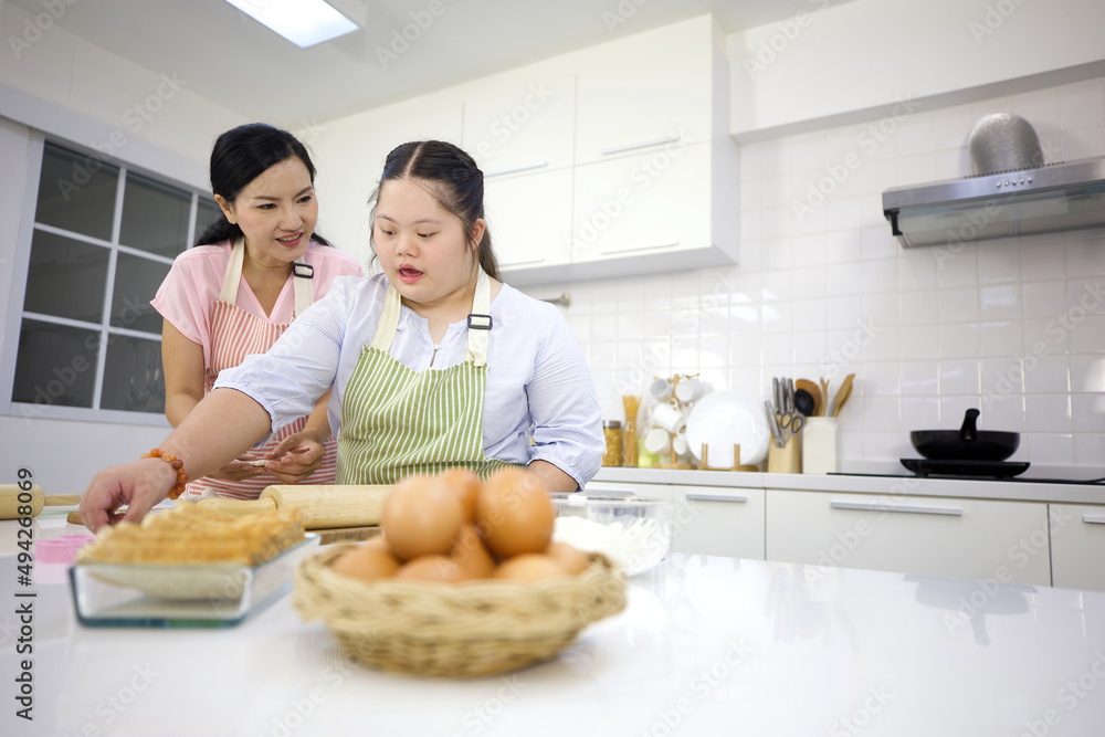mother support down syndrome teenage girl or her daughter making thresh flour for make a bread in a kitchen mother support down syndrome teenage girl or her daughter making thresh flour for make a bread in a kitchen