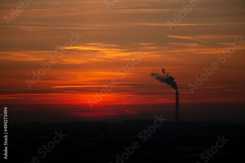 Red-orange sky. Pipe from the factory with smoke. Silhouette © Polina K