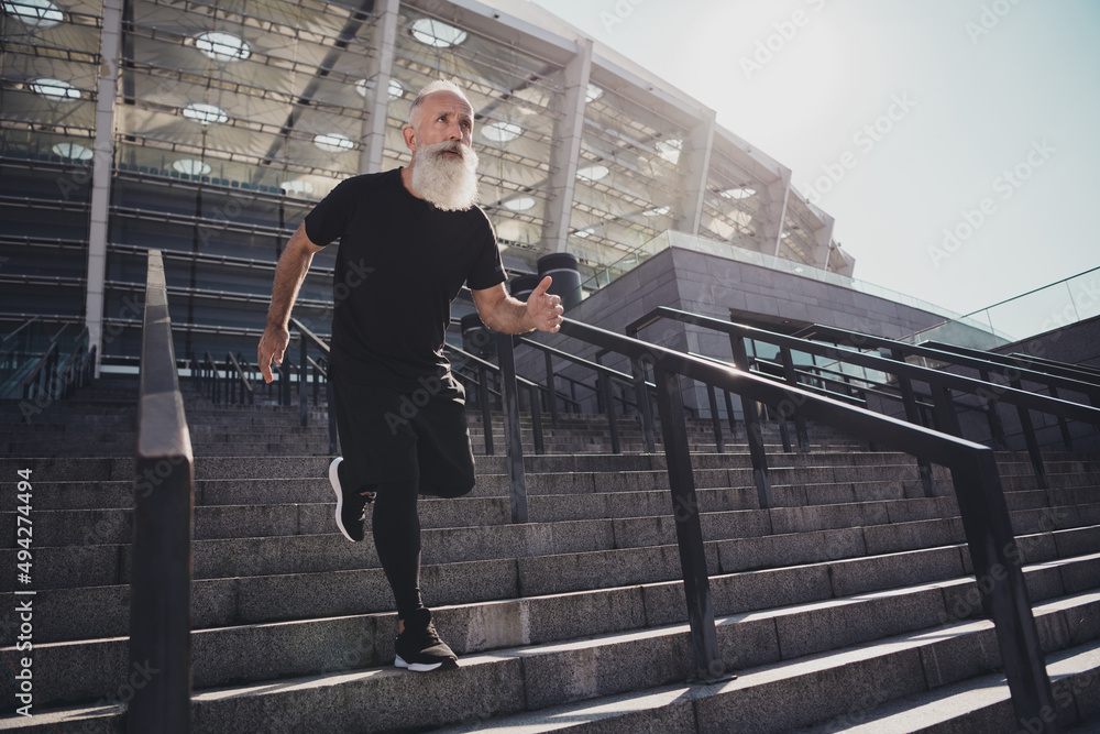 Full length body size view of attractive virile confident motivated grey-haired man running downstairs developing spirit outdoors