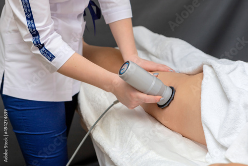 The specialist in a white coat "Medicine for life" gives the client an anti-cellulite massage using a special device.Ultrasonic cavitation of the body contouring treatment