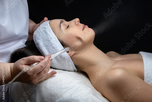 A cosmetologist does a gas-liquid peeling procedure for a young girl.A girl in the cosmetologist's office during the procedure.Face and neck care in a beauty salon.Cosmetic procedures for the face