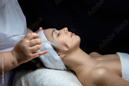 A cosmetologist does a gas-liquid peeling procedure for a young girl.A girl in the cosmetologist's office during the procedure.Face and neck care in a beauty salon.Cosmetic procedures for the face