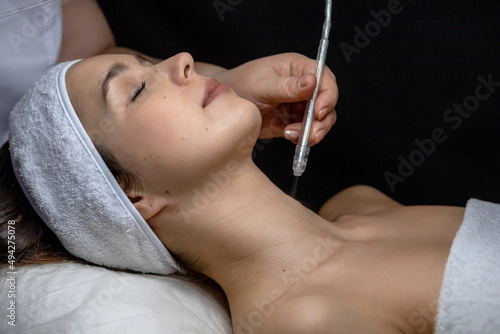 A cosmetologist does a gas-liquid peeling procedure for a young girl.A girl in the cosmetologist's office during the procedure.Face and neck care in a beauty salon.Cosmetic procedures for the face
