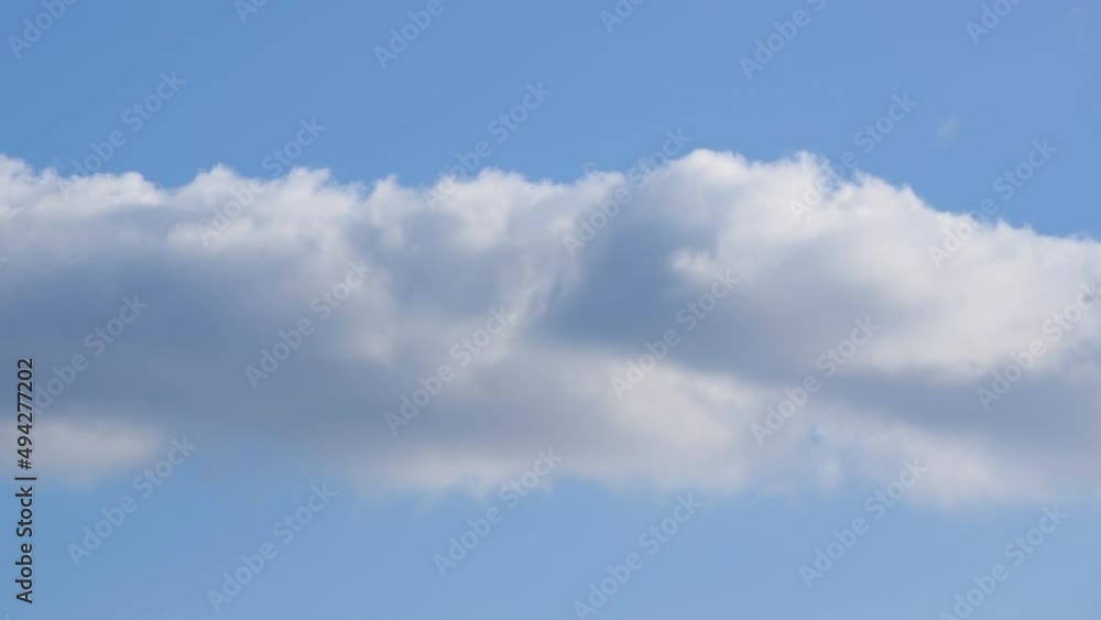 Cumulus cloud moving across blue sky from left to right, fair weather Cumulus cloud moving across blue sky from left to right, fair weather