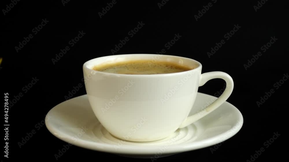 Falling sugar into a cup of coffee on a black background. Slow motion. Falling sugar into a cup of coffee on a black background. Slow motion.