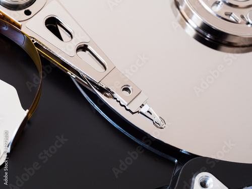 A close-up of a computer HDD hard drive disassembled, showing the actuator arm and platter disc Fototapeta