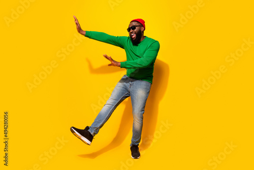 Photo of glad funny nice man dance enjoy discotheque wear sunglass red beanie green shirt isolated yellow color background