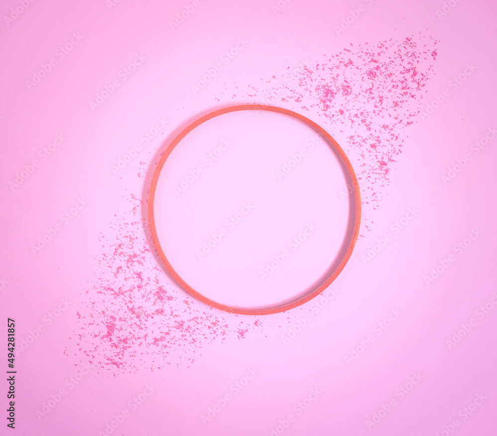 Wooden ring and colored sand lay down on a pastel pink background. Square flat lay composition with copy space, minimal decorative retro style concept