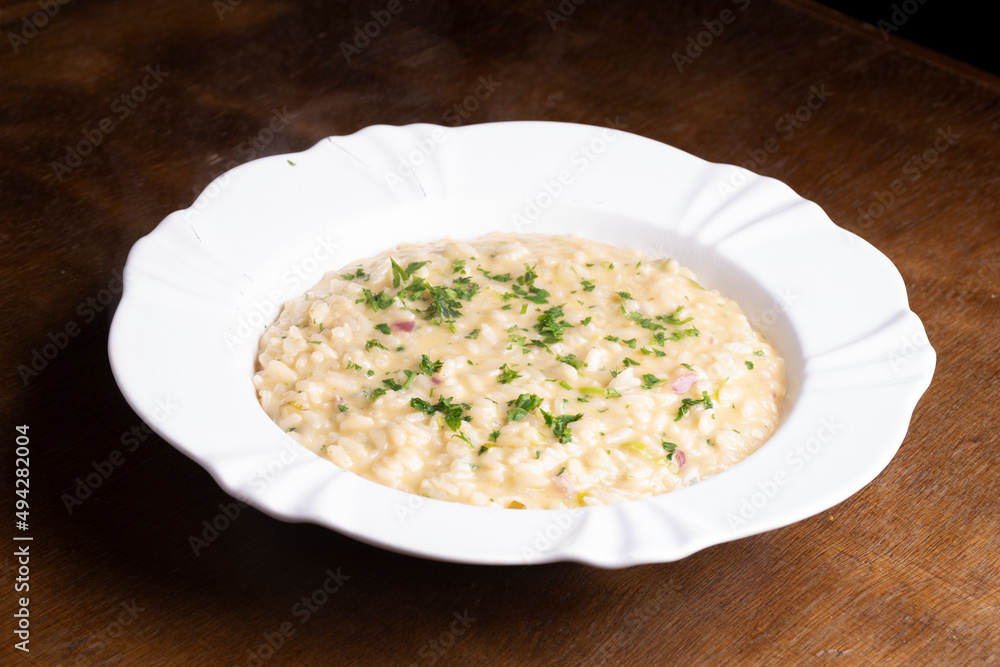 plate of risotto with green onions on wooden table plate of risotto with green onions on wooden table