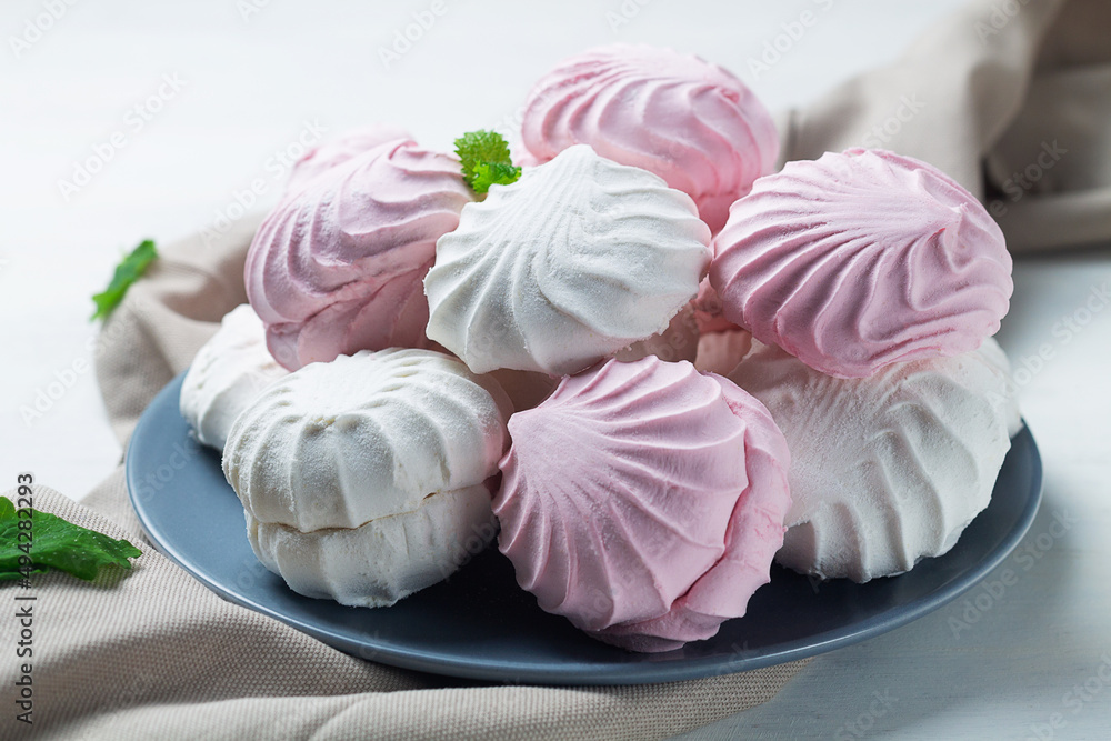 Pink and white Marshmallow dessert zephyr on the table. Meringue dessert with green mint in a grew plate on the white background. traditional Russian sweet dessert. copy space Pink and white Marshmallow dessert zephyr on the table. Meringue dessert with green mint in a grew plate on the white background. traditional Russian sweet dessert. copy space