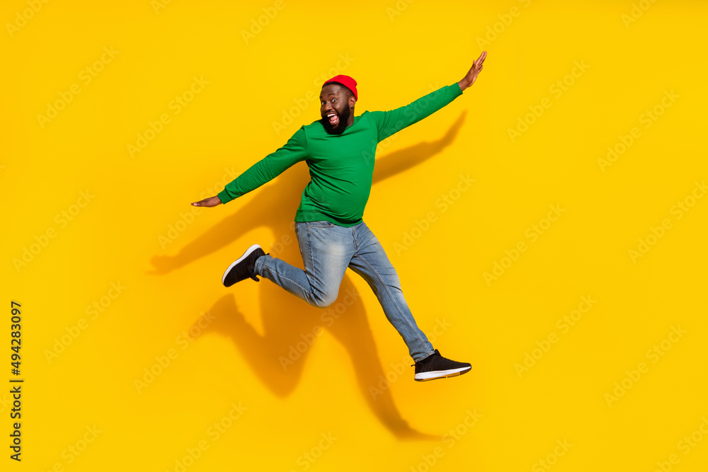 Photo of carefree inspired cheerful guy jump plane pose wear red beanie green shirt isolated yellow color background