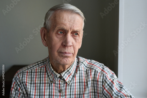 Handsome elderly man 80 years old, sad, pensive, looks out the window. 