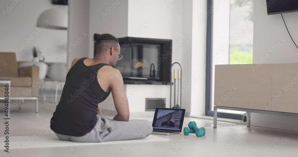 African American fitness trainer using laptop for online training with client during coronavirus pandemic. African American fitness trainer using laptop for online training with client during coronavirus pandemic.