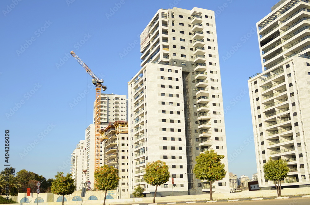 Construction site and crane. Orange trees around new houses. Modern residential buildings. New cozy quarters.