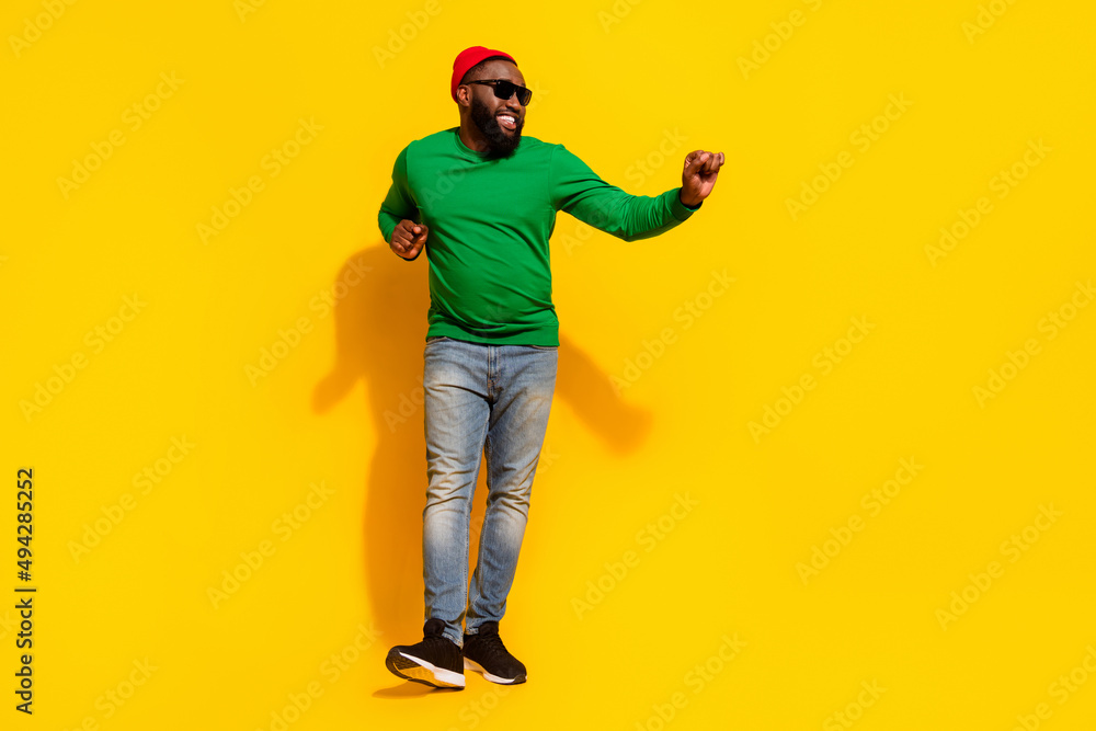 Fototapeta premium Photo of crazy cheerful dancer man have weekend fun wear sunglass red beanie green shirt isolated yellow color background