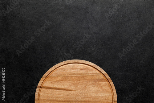 Part of cutting wooden round board on dark background, top view, space to copy text.