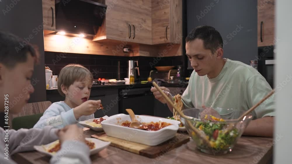 Young happy family talking while having dinner at home table. Young happy family talking while having dinner at home table.