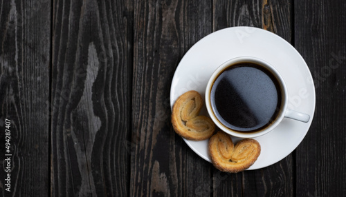 black espresso coffee from ground beans with heart-shaped cookies on a dark wooden background copy space, flat lay