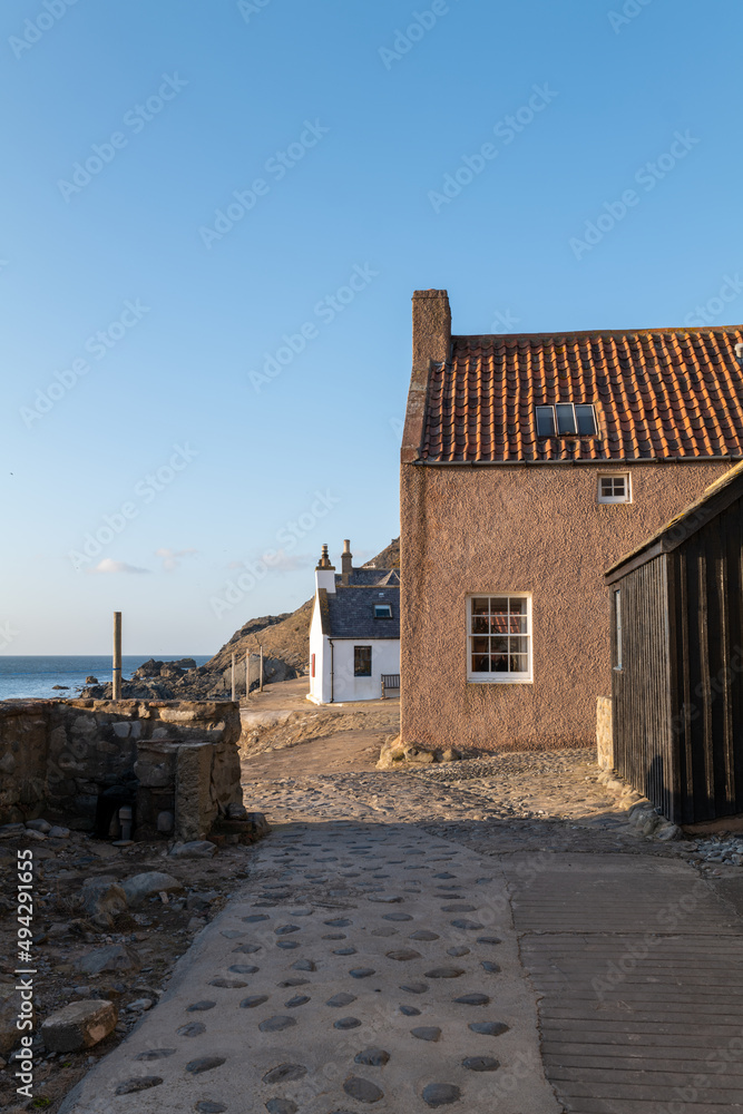 Obraz premium 20 March 2022. Crovie, Aberdeenshire, Scotland. This is the row of houses that was the old coastal fishing village of Crove carching the Sun. The ver small village is now mostly holiday homes.