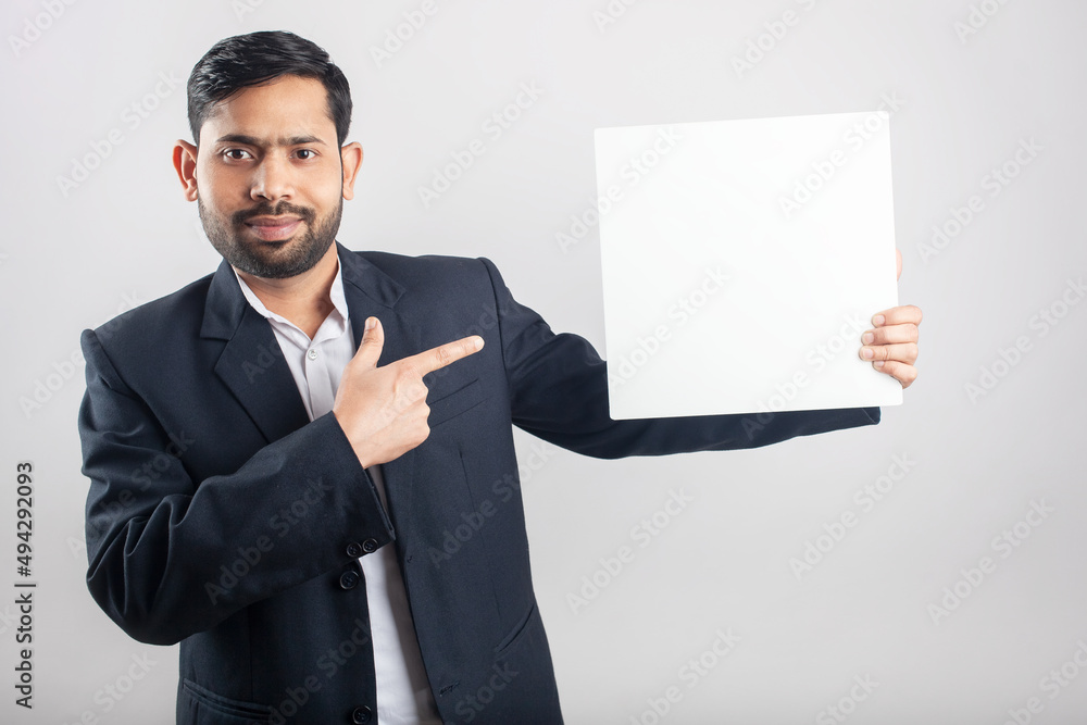 young adult indian man showing a white empty board and pointing finders young adult indian man showing a white empty board and pointing finders