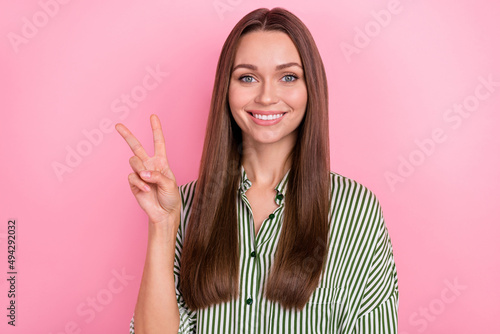 Photo of pretty cute woman wear striped shirt smiling showing v-sign isolated pink color background © deagreez