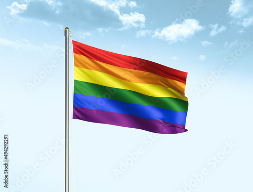 LGBT flag waving in blue sky with clouds. LGBT flag. 3D illustration © Stalvalki