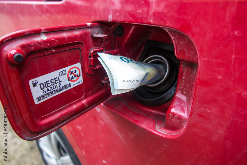 Fototapeta premium Banknotes, euro in the fuel filler of a red car.