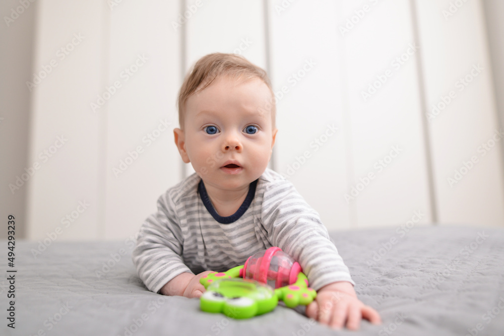 Baby boy playing with toys indoors at home. Cute little five month old baby boy, playing at home in bed in bedroom. Baby boy playing with toys indoors at home. Cute little five month old baby boy, playing at home in bed in bedroom.
