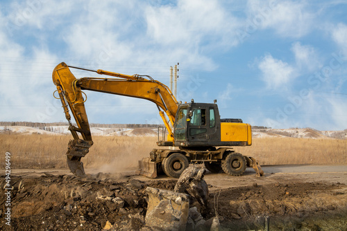 A working excavator with attachments on the construction of a road junction.