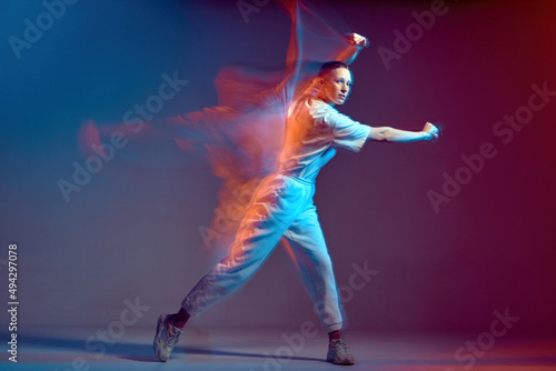 Dancing modern energetic sports girl moving, waving hand. Breakdancer in colourful neon studio light. Long exposure
