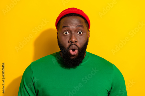 Portrait of attractive amazed stunned funny guy wearing cap staring eyes pout lips isolated over vivid yellow color background
