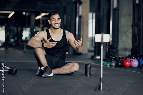 Handsome Arab Male Fitness Blogger Recording Video At Smartphone Camera At Gym