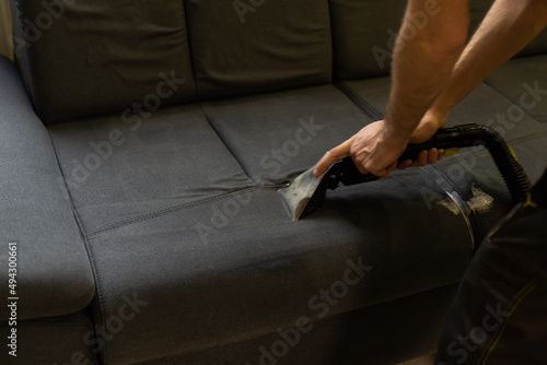 Hand cleaning a sofa with a steam cleaner, Home cleaning concept photo