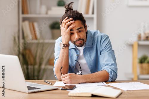 Frustrated young african american   suffering from headache   feeling stressed with work at laptop photo